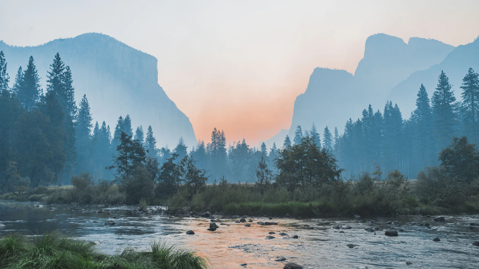 River flowing through a hazy mountain valley at sunset