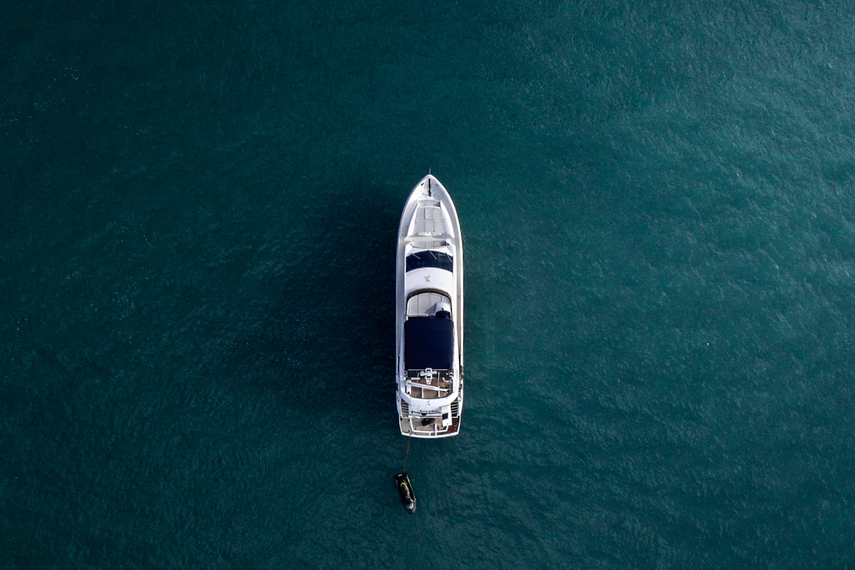 Aerial view of a small motorboat idling on dark green water