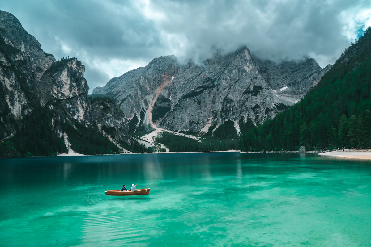 Two people in a small rowboat on a turquoise alpine lake