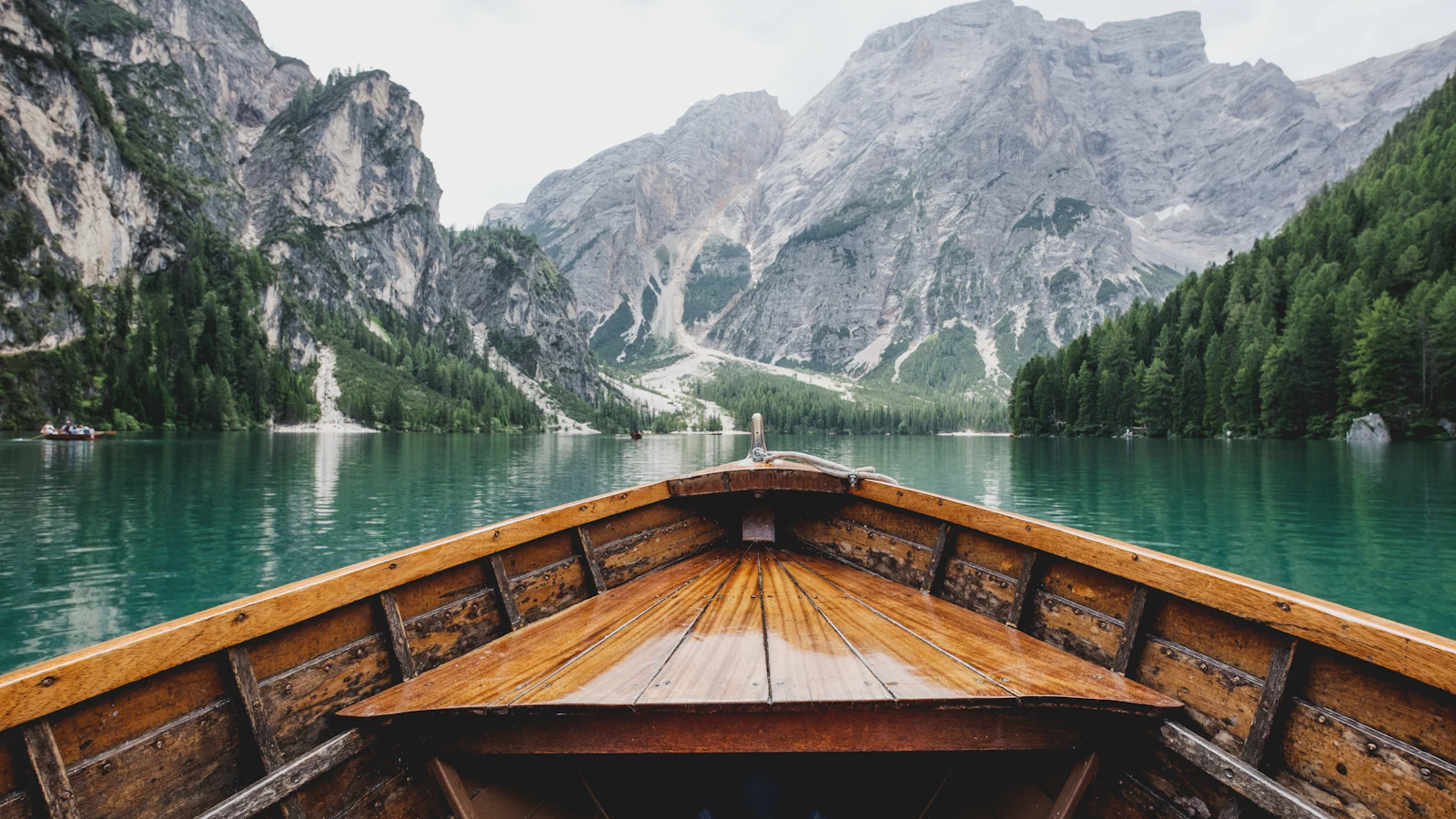 Bow of a wooden boat gliding across a clear alpine lake